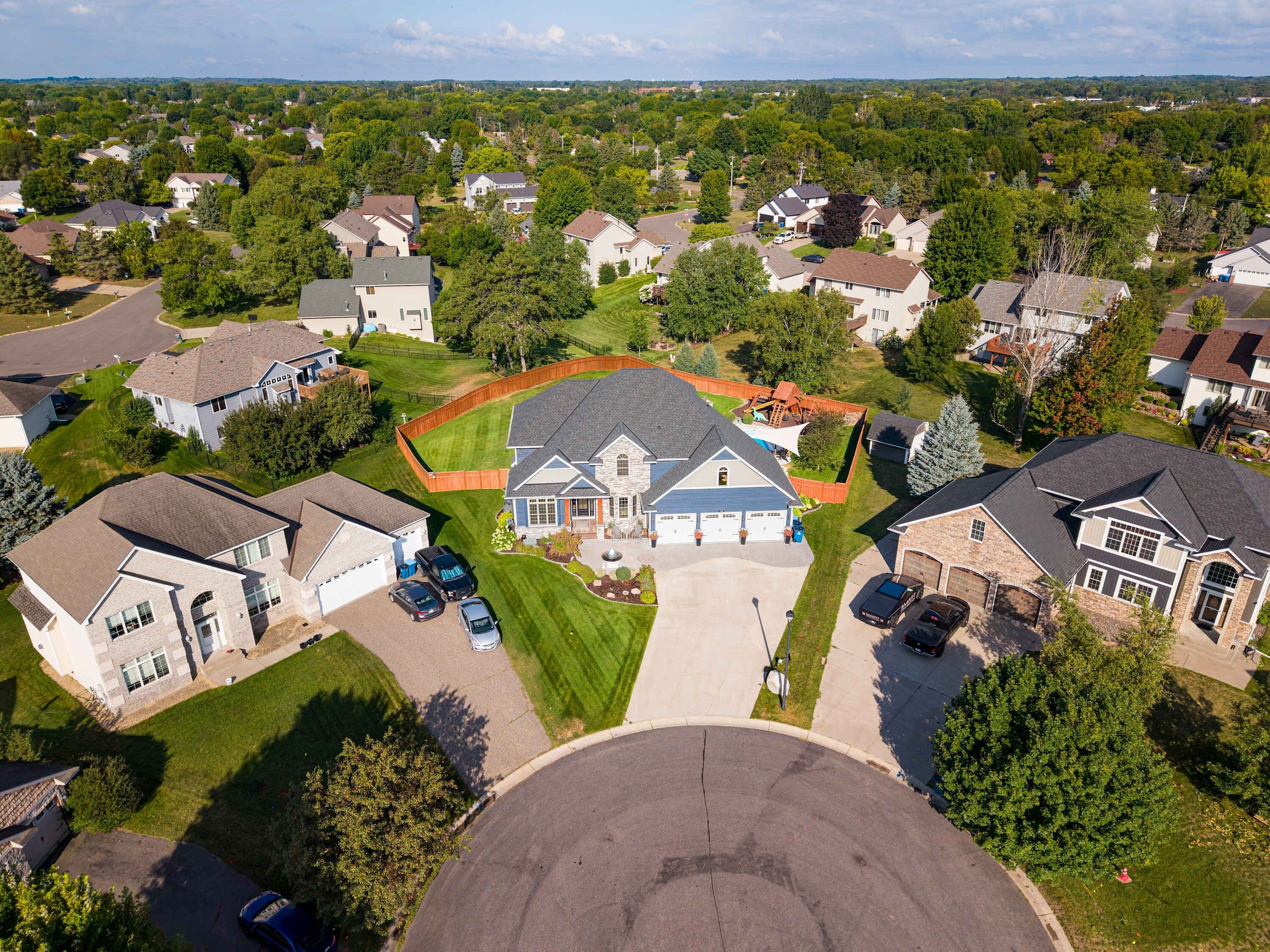 A residential area with houses, a large driveway, and a fenced yard.