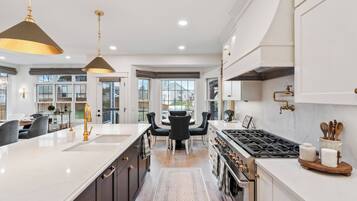 A modern kitchen with a central island, dark cabinetry, and stainless steel appliances.