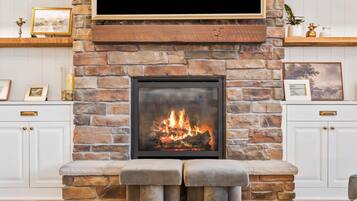 Una chimenea con pared de piedra, un televisor montado encima y cuadros en ambos lados.