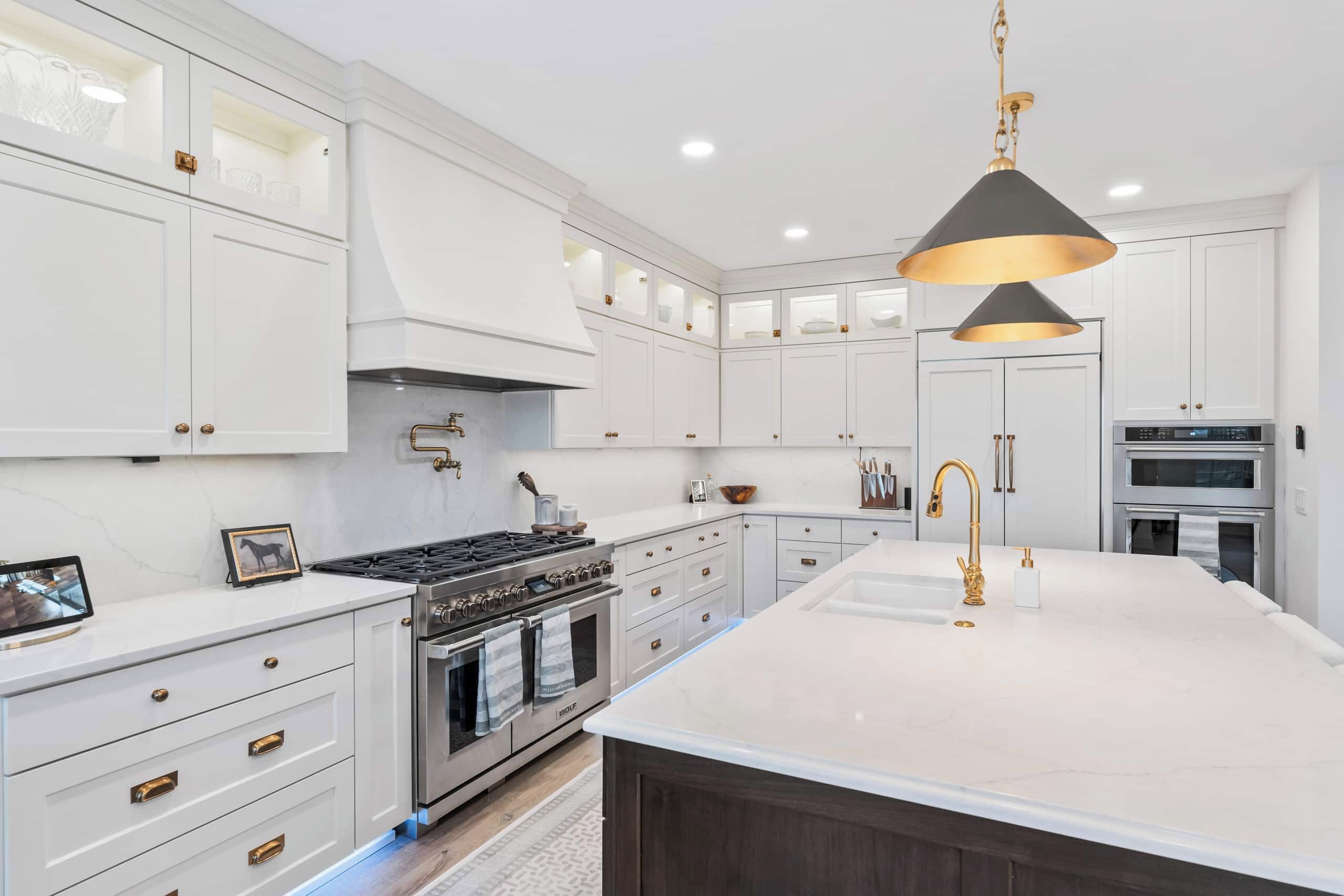 A modern kitchen with white cabinetry, stainless steel appliances, and a central island with a black pendant light.