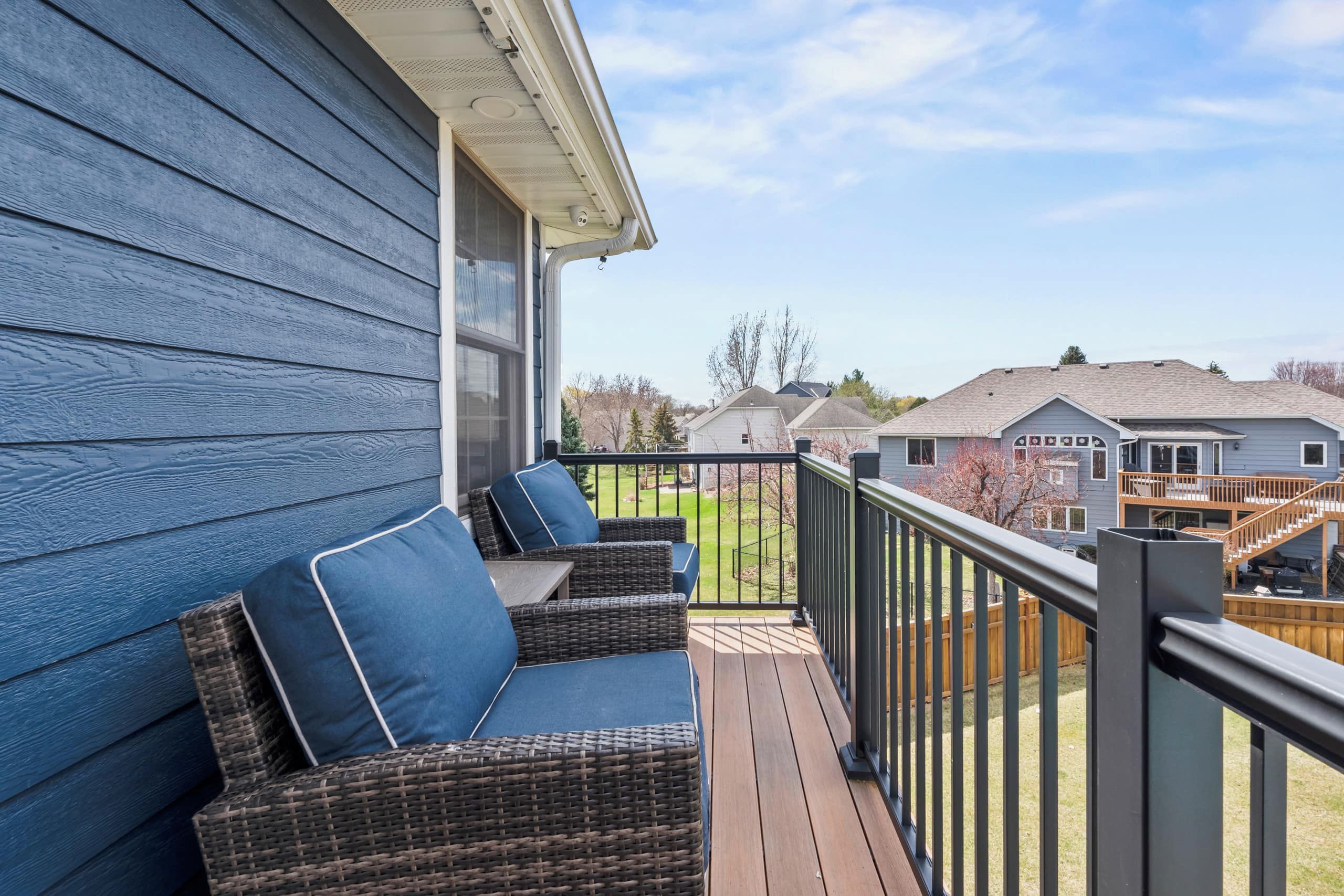 A wooden deck with wicker furniture and a metal railing.