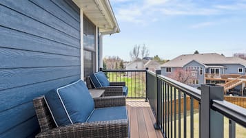 A wooden deck with wicker furniture and a metal railing.