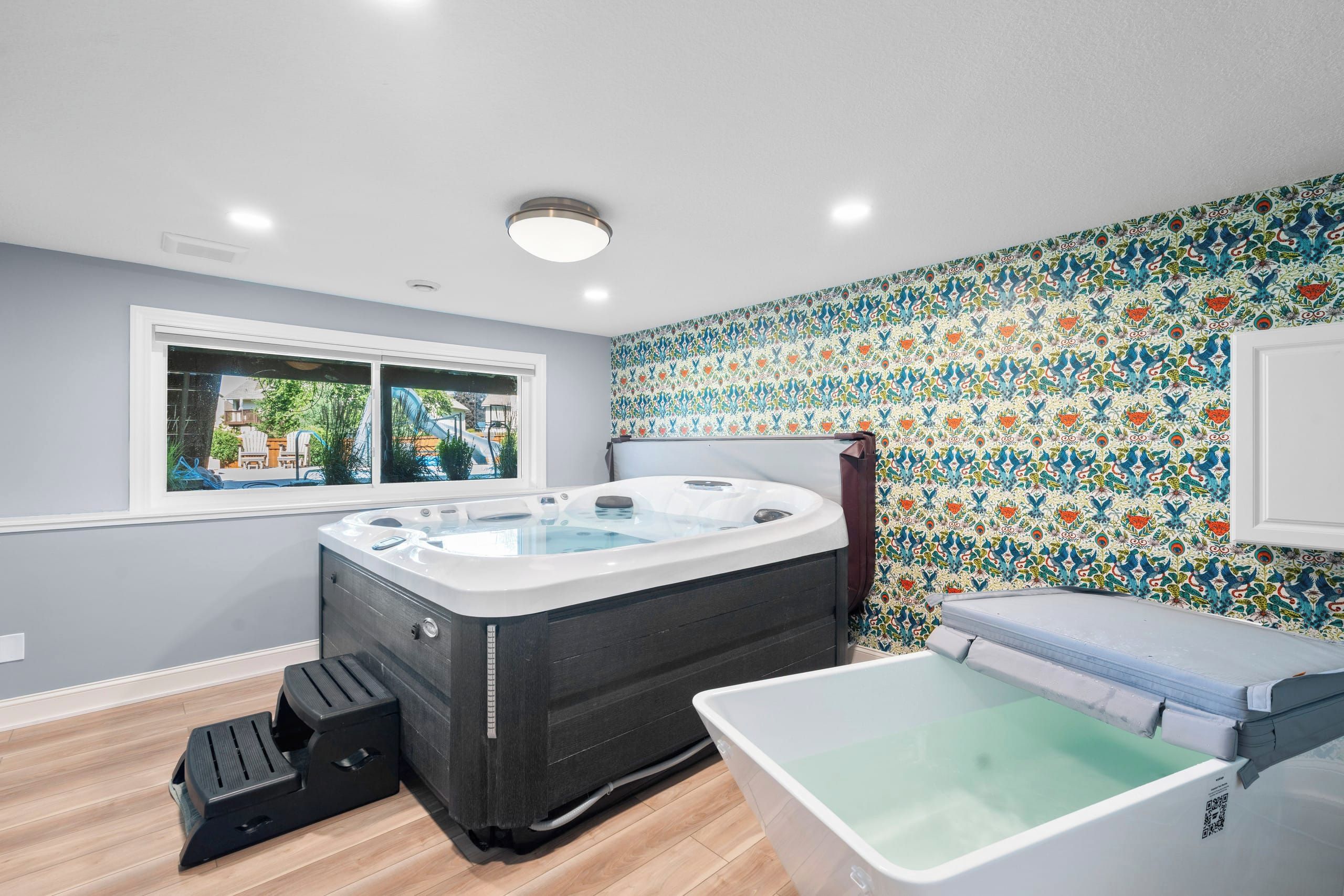 A bathroom with a hot tub, a shower, and a window with a view of the outdoors.