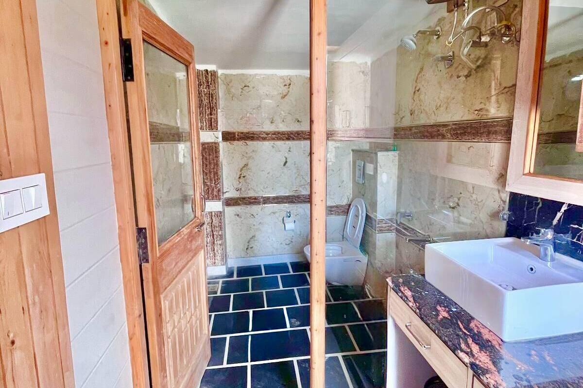 Une salle de bain avec une porte en bois, un lavabo blanc et des toilettes.