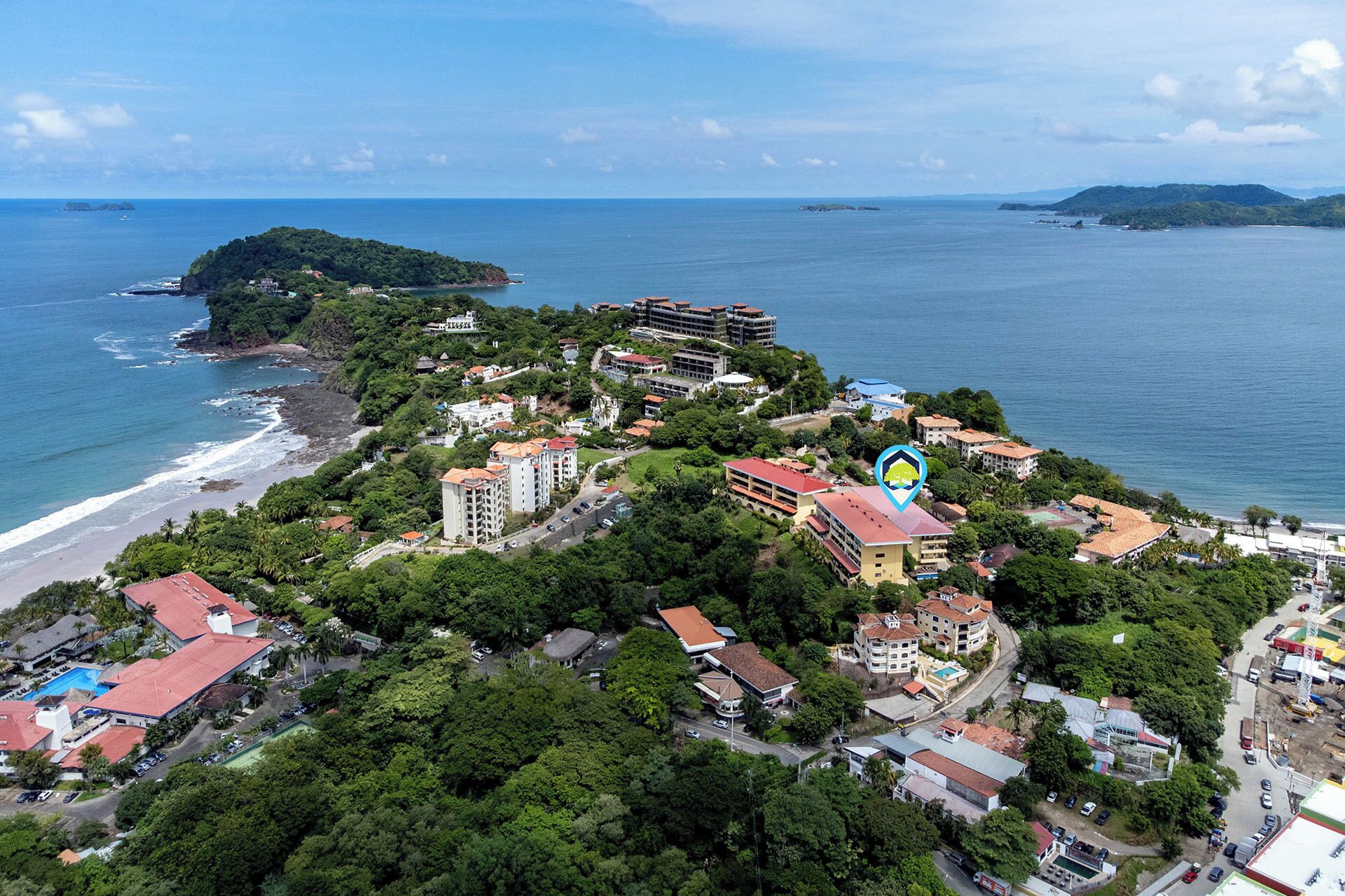 An aerial view of a coastal town with buildings, a beach, and a small island in the distance.