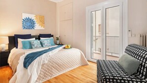 A bedroom with a bed, bedside table, and a view of the balcony. - Stylish apt steps from Acropolis by GHH (Athens)