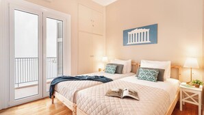A hotel room with two beds, a balcony, and a view of a classical building. - Stylish apt steps from Acropolis by GHH (Athens)