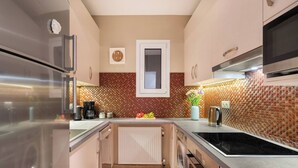 A modern kitchen with stainless steel appliances, a tiled backsplash, and a central island with a vase of flowers. - Stylish apt steps from Acropolis by GHH (Athens)