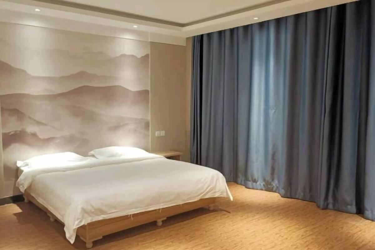 A bedroom with a bed, wooden floor, and a wall with a wavy pattern.