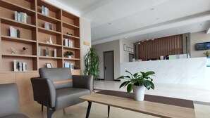 A modern lobby with a sofa, a wooden table, and a bookshelf. - Homeinn Pebble Hotel (Zhengding Airport) (Zhengding)