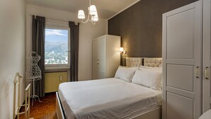 A bedroom with a bed, wardrobe, and a view of the city through a window. - Casa Lucia a Rapallo (Rapallo)