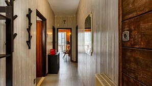 A hallway with wooden walls, a black bench, and a door with a window. - Casa Lucia a Rapallo (Rapallo)