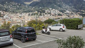 A parking lot with a scooter, a white car, and a black SUV. - Casa Lucia a Rapallo (Rapallo)
