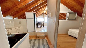 A compact, attic-style room with a kitchenette, a small dining area, and a bed. - Bella Vista Junior in Kamena Vourla (Kamena Vourla)