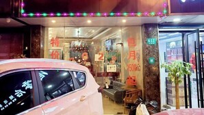 Un escaparate con un letrero de neón, un coche estacionado adelante y un cartel que indica la habitación 612.