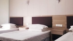 Una habitación de hotel con dos camas, un cabecero de madera, una mesita de noche y una lámpara de pared.