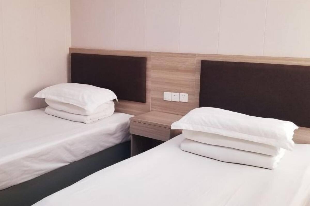 Two single beds with wooden headboards, white bedding, and a nightstand between them.