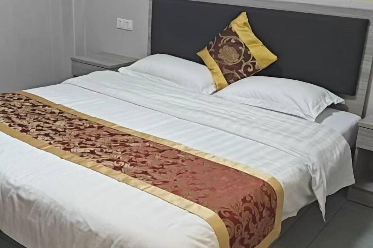 A neatly made bed with a patterned bedspread, a pillow with a decorative design, and a headboard.