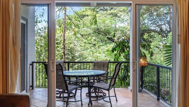 A balcony with a glass door, a round table, and four chairs. - 3-BD Beauty with Pool Near Beach (Tempate)