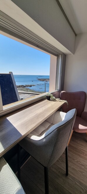 Una habitación con un escritorio de madera, una computadora portátil y vista al mar a través de una ventana.