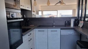 Eine moderne Küche mit weißen Schränken, Edelstahlgeräten und Holzboden.