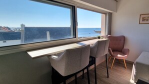 Ein Zimmer mit Meerblick, einem Schreibtisch mit zwei Stühlen und einem Sofa.