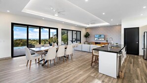 Une cuisine moderne dotée d’un îlot central, de grandes fenêtres et offrant une vue sur l’extérieur.
