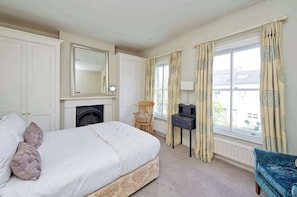 Enjoy a cozy stay with a large bed, wooden chair, and small table, plus a fireplace and window with a view.