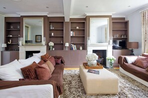 Relax in this stylish living room with a large sofa, ottoman, and shelves for your belongings.