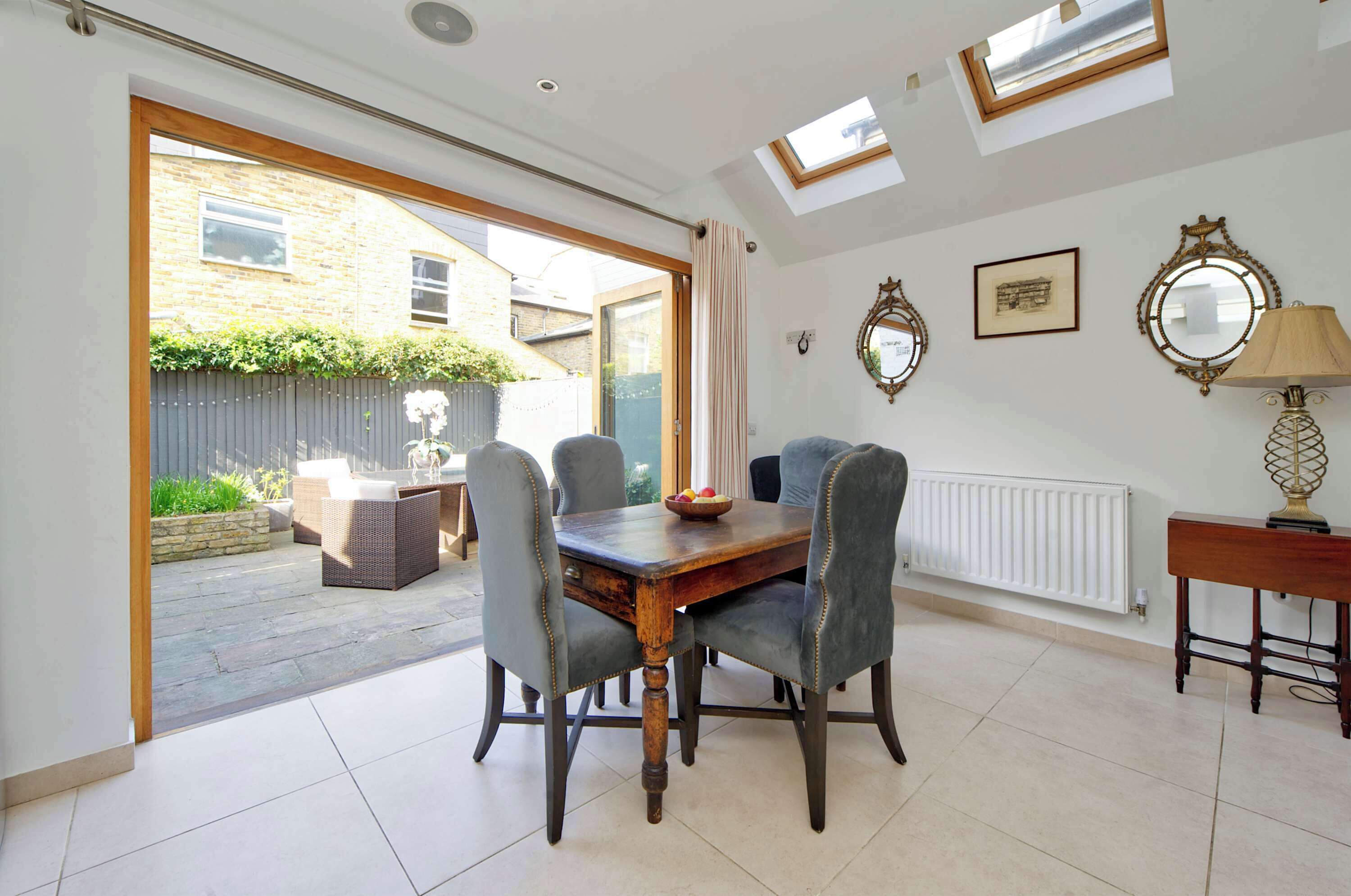 A dining area with a table and chairs, a window, and a radiator.