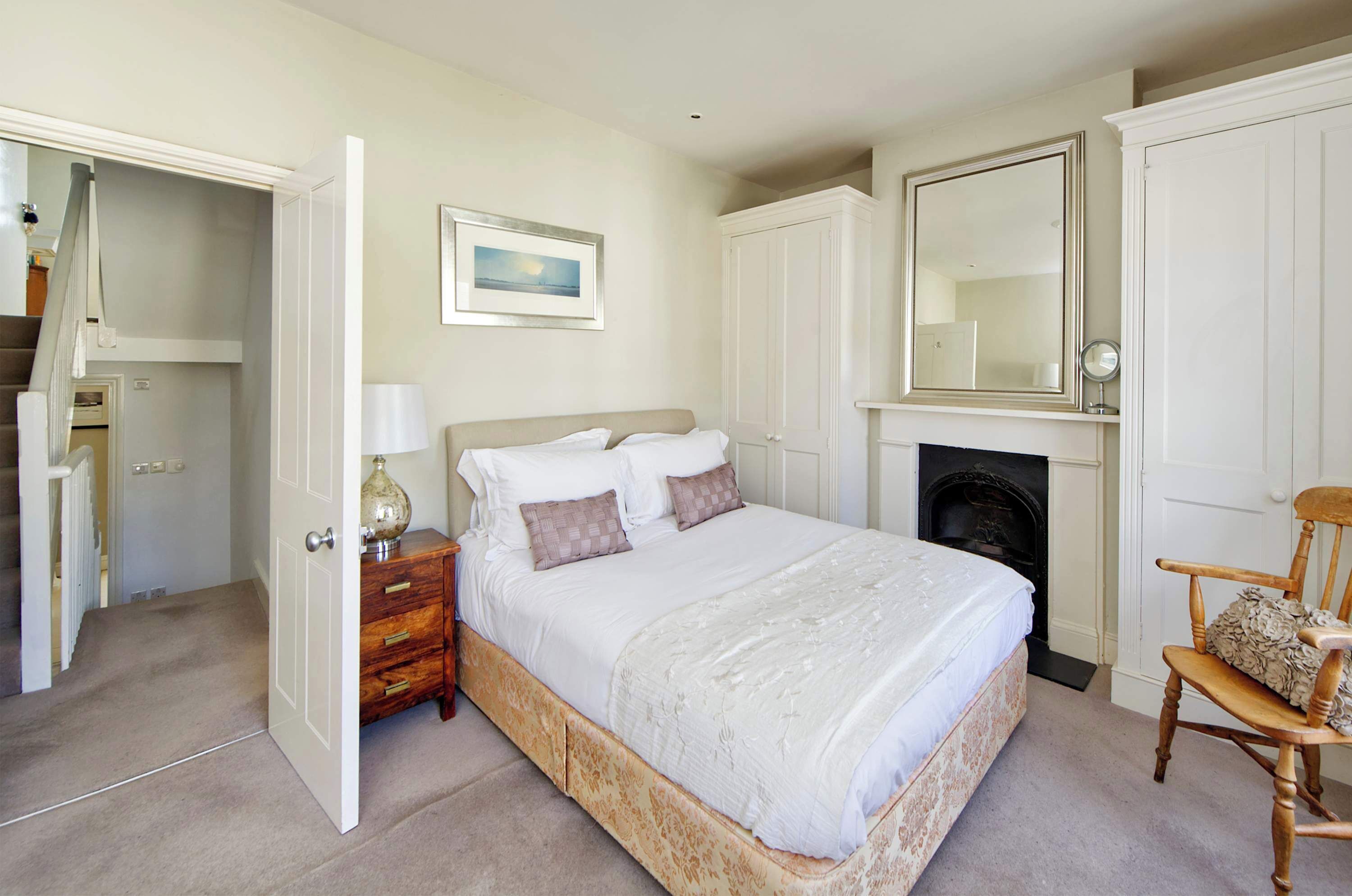 A bedroom with a bed, a chair, a fireplace, and a wardrobe.