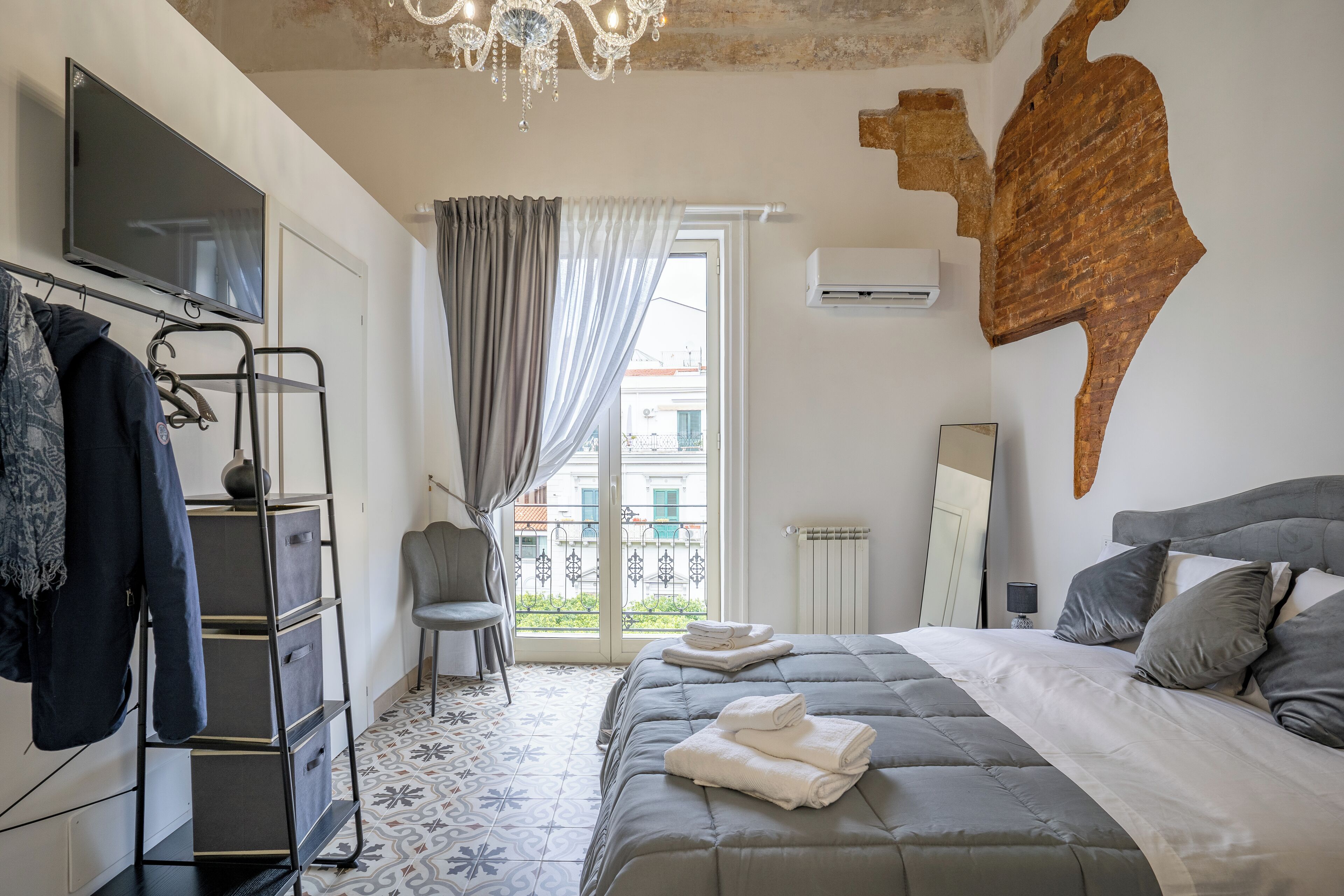 Ein Hotelzimmer mit Bett, Fernseher, Kleiderschrank, Stuhl und einem Balkon mit Blick.
