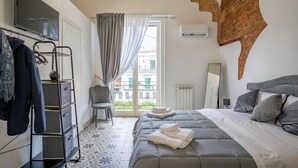 Ein Hotelzimmer mit Bett, Fernseher, Kleiderschrank, Stuhl und einem Balkon mit Blick.