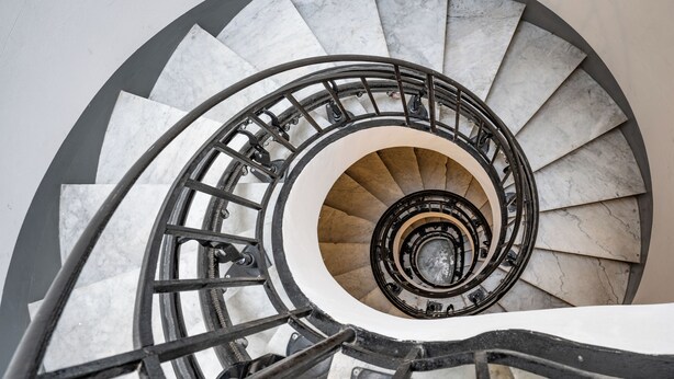 Eine Wendeltreppe mit Marmorverkleidung und schwarzen Metallgeländern.