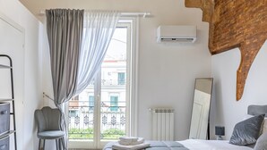 Ein Schlafzimmer mit einem großen Bett, einer Kristallleuchtre, einer Wandpaneele aus Holz, einem Fenster mit Vorhängen und einer Heizkörper.