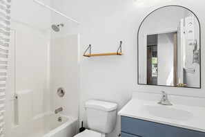 Ein Badezimmer mit Badewanne, Toilette und Waschbecken mit Spiegel darüber.