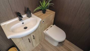 Un baño pequeño con un lavabo blanco, un mueble de madera y un inodoro.