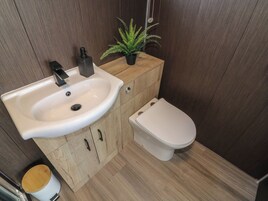 Un baño pequeño con un lavabo blanco, un mueble de madera y un inodoro.