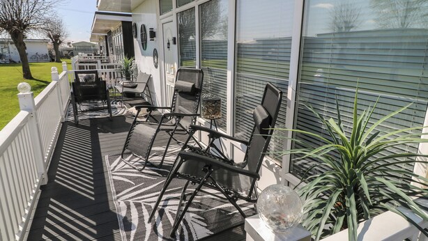 Un espacio al aire libre cubierto con un patio, dos sillas, una mesa y una planta en maceta.