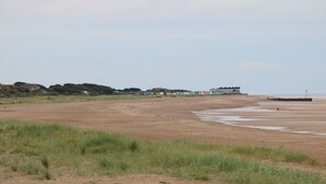 Una extensa playa arenosa con algunos edificios al fondo.