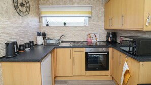 Una cocina moderna con armarios de madera, encimera negra, horno empotrado, microondas y un reloj de pared grande.