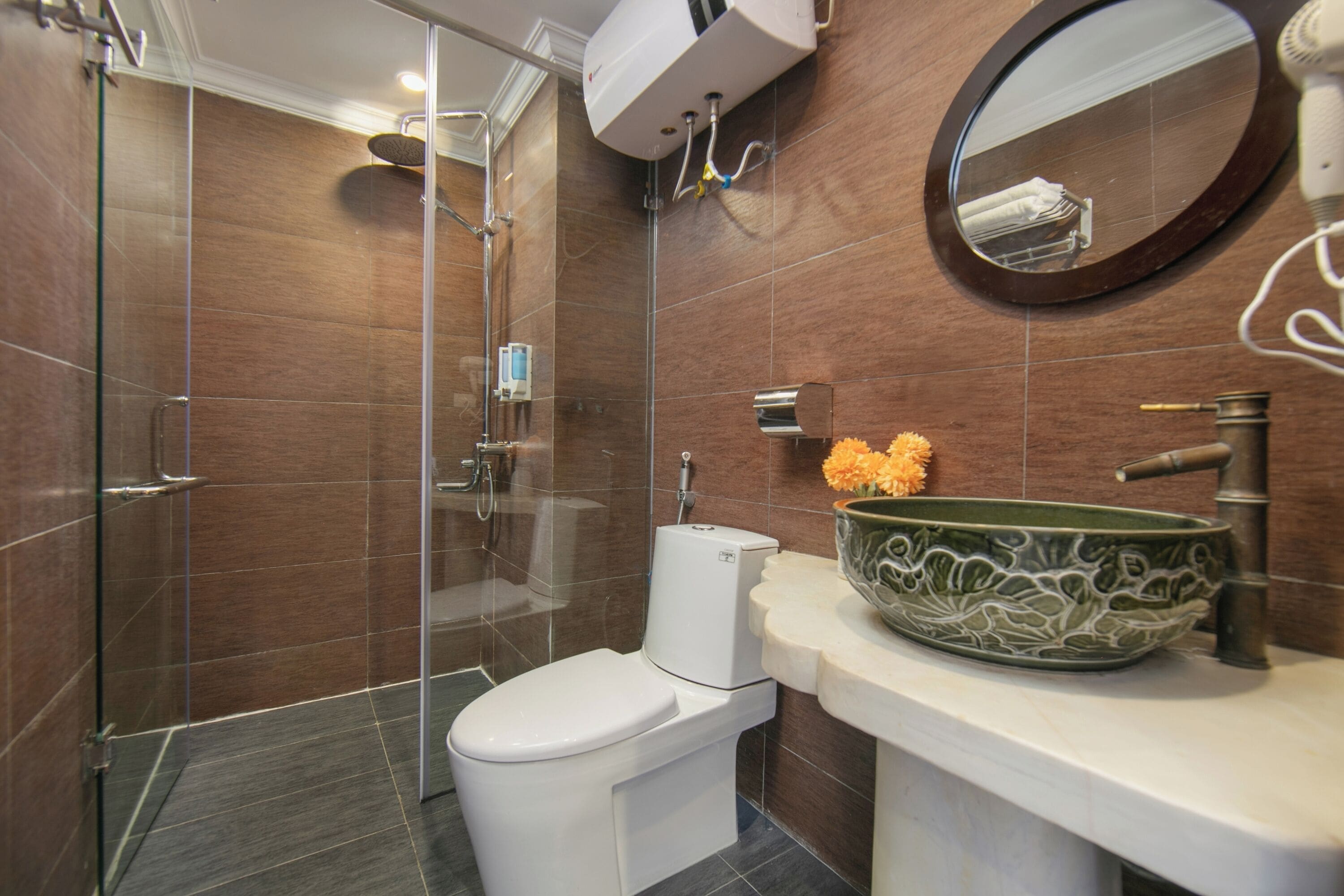 Ein modernes Badezimmer mit einer gläsernen Dusche, einer weißen Toilette, einem grünen Waschtisch und einem runden Spiegel.