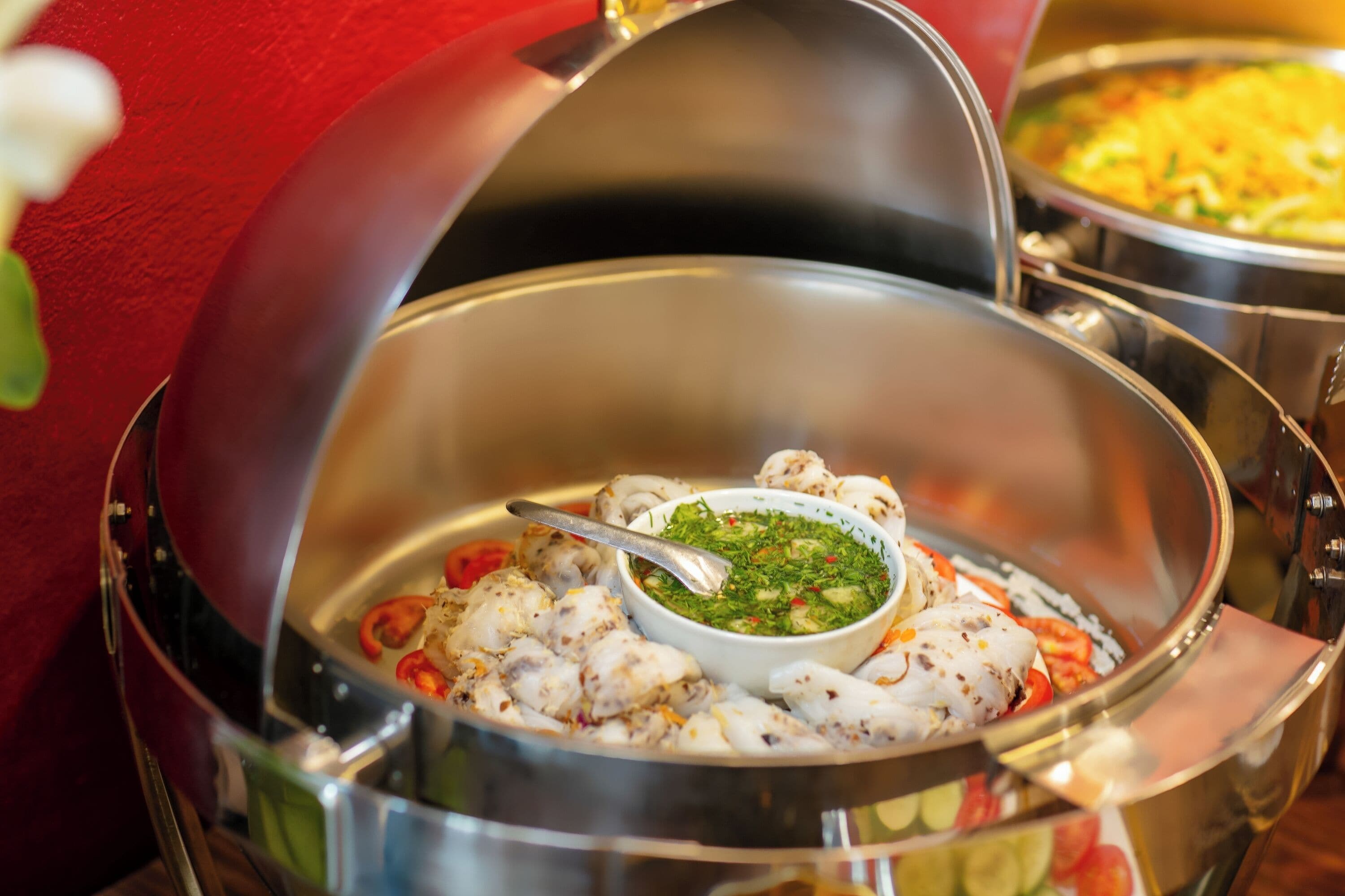 A seafood dish with a dipping sauce in a metal bowl.