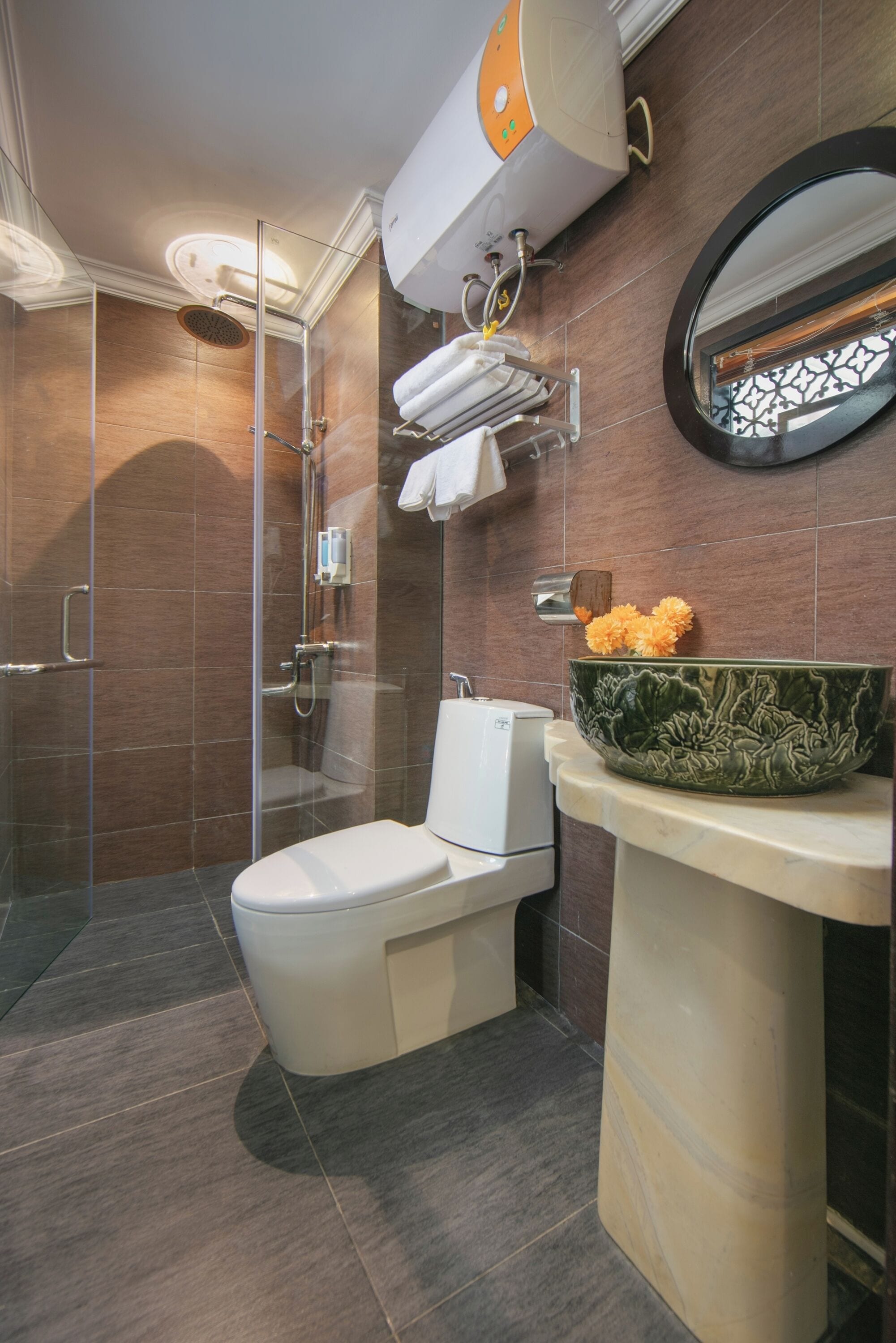Un ba ño moderno con ducha de vidrio, inodoro y lavamanos con un recipiente decorativo.