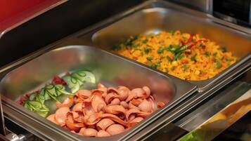 A buffet with various food items including sliced ham and a rice dish.