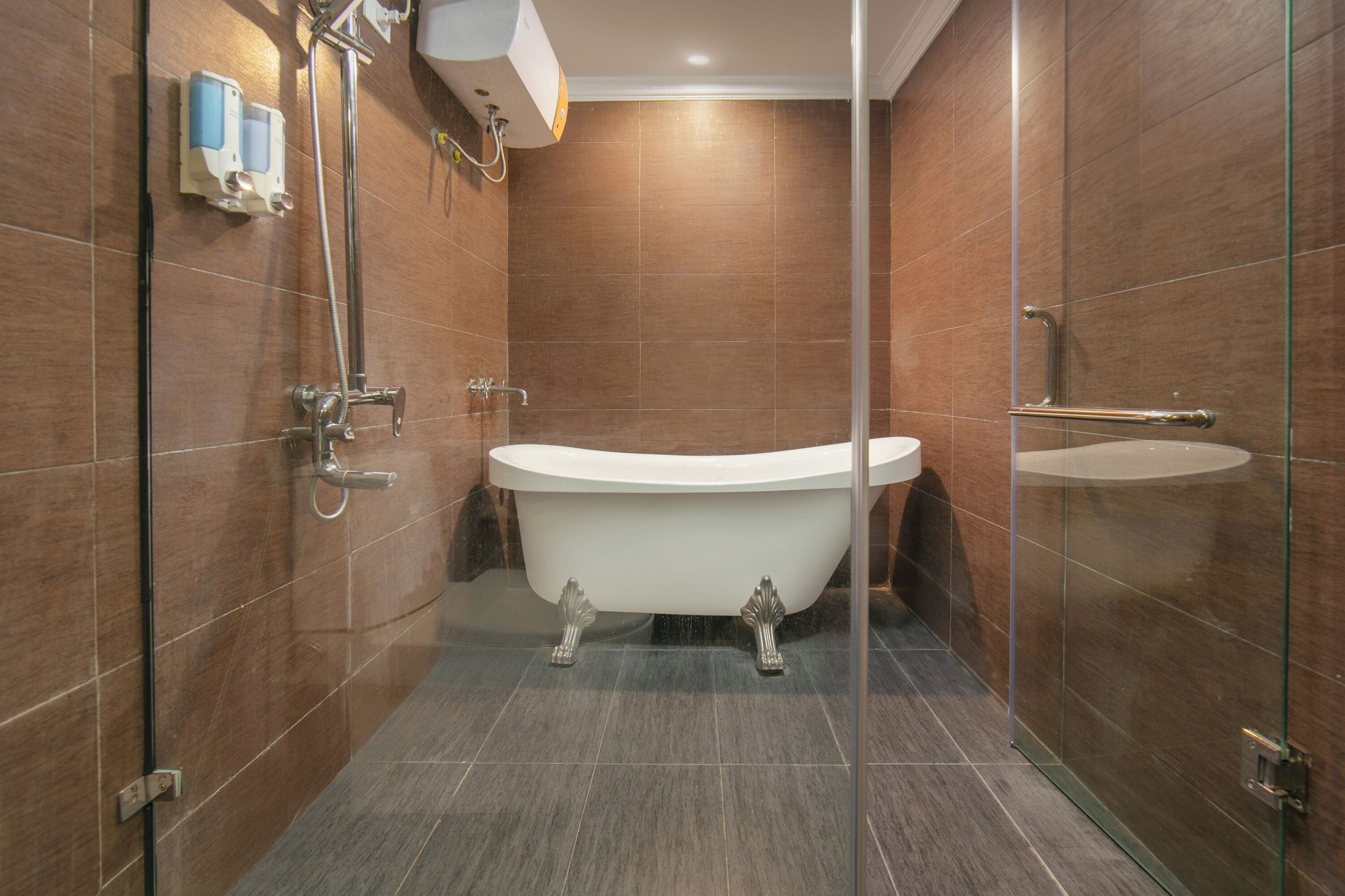 Une salle de bain moderne avec une baignoire sur pieds, une douche à parois de verre et un distributeur de savon fixé au mur.