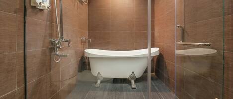 A modern bathroom with a freestanding bathtub, a glass shower enclosure, and a wall-mounted soap dispenser.