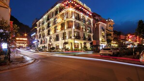 Un hotel de varios pisos con letreros iluminados, balcones y una fachada bien iluminada.