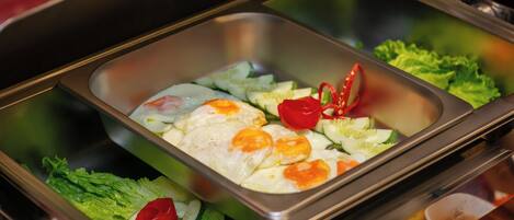 Un bufé con diferentes opciones de comida, como huevos, lechuga y tomates.