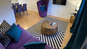 A modern living room with a purple sofa, a round coffee table, and a black and white patterned rug. - 2 Bed-sleeps 3-parking-town Centre (Northallerton)